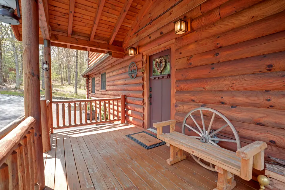 Covered front porch with log railings and a wagon wheel bench