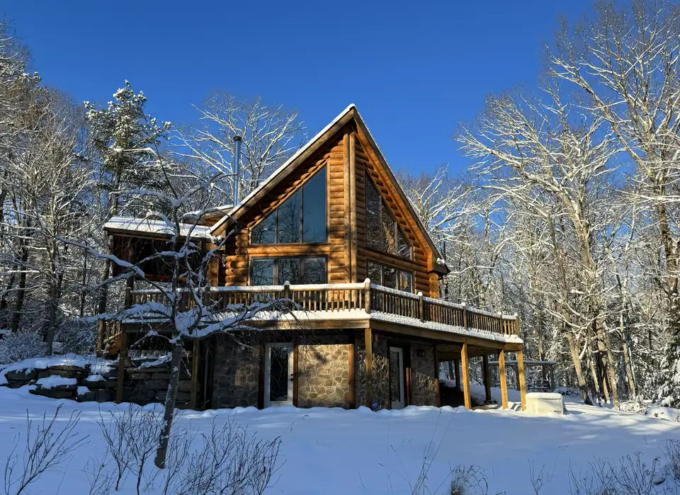 Fernwood Lodge log cabin after a fresh snowfall with snow on the deck and trees