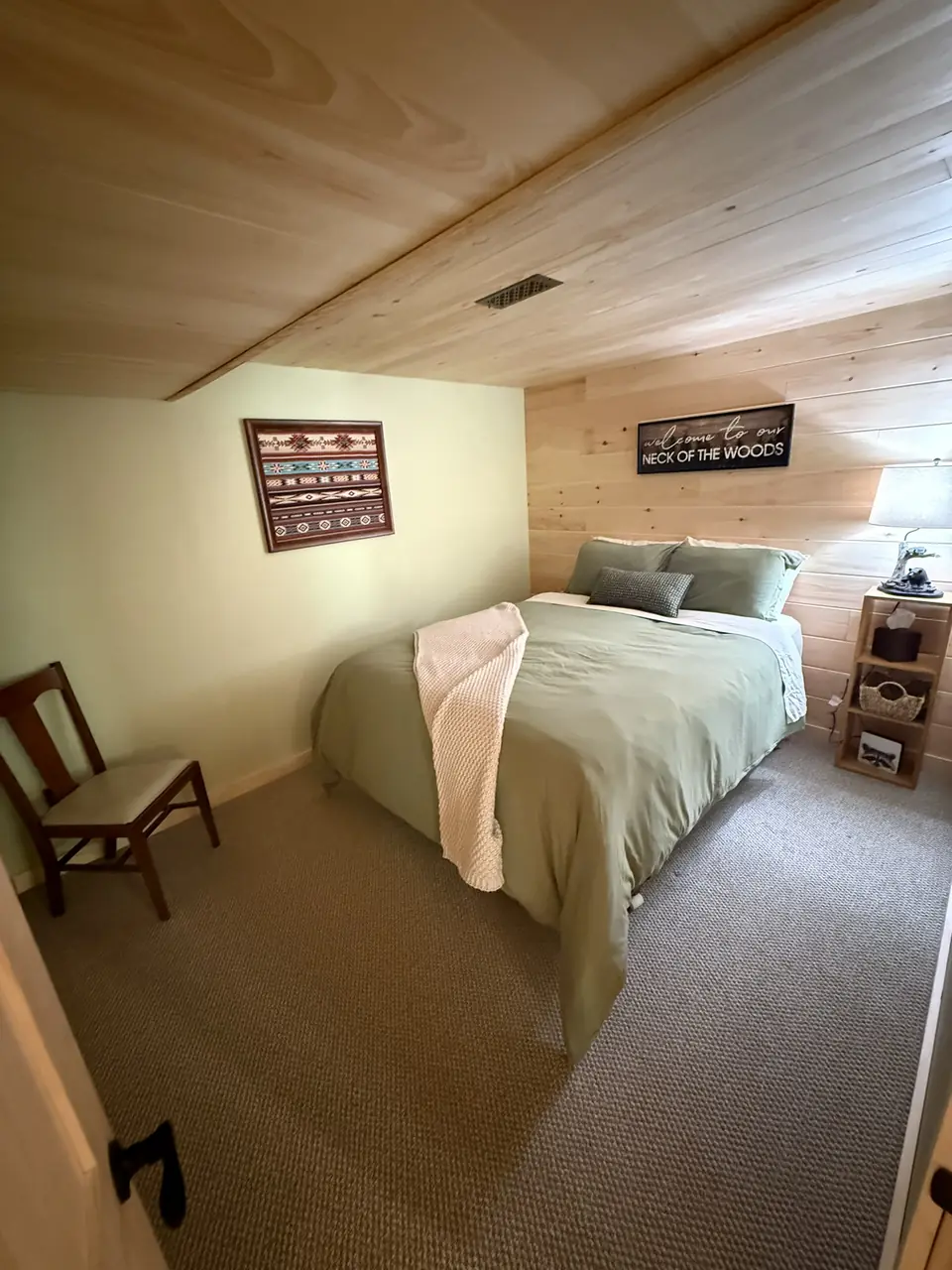 Lower level bedroom with pine paneling and soft bedding