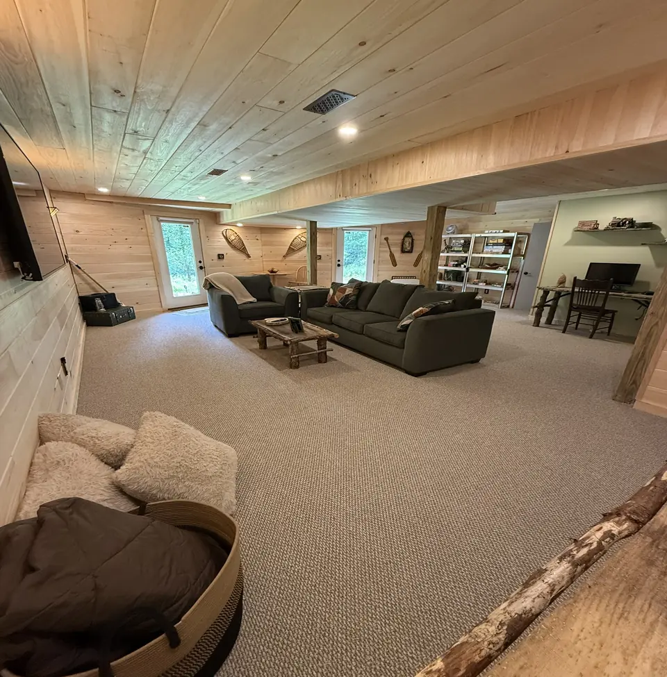 Finished lower level lounge with carpet, pine ceiling, and bookshelves