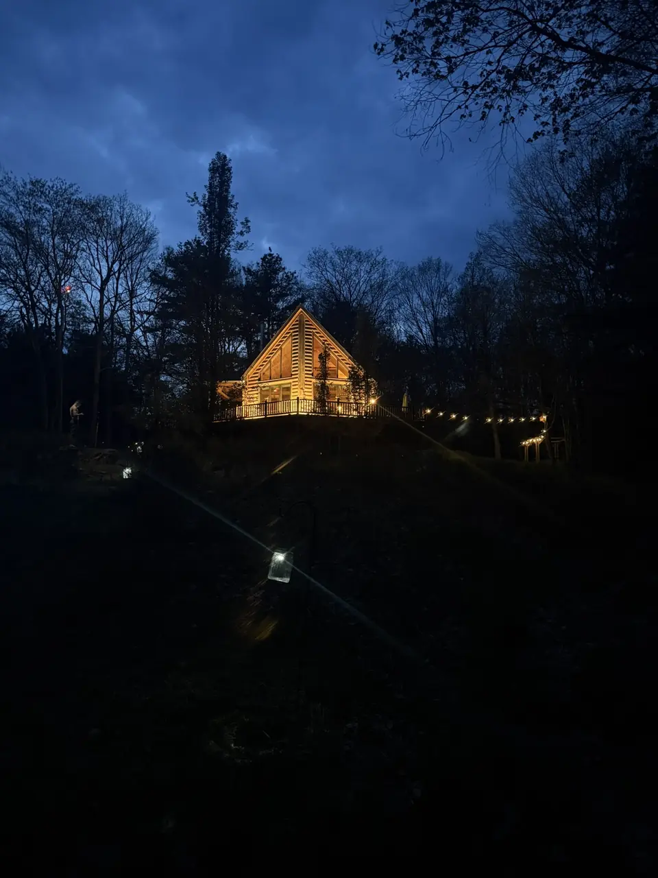 The cabin glowing at night through the dark woods