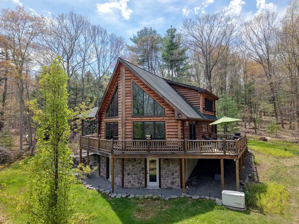 Log cabin and wraparound deck among new spring leaves